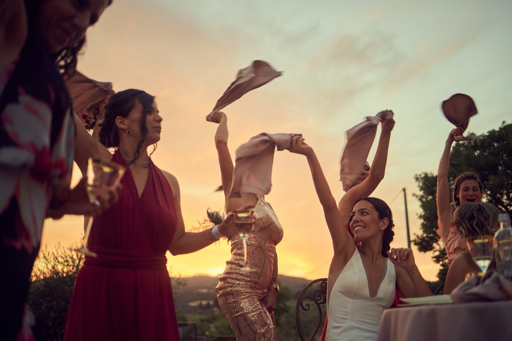 Invitati che agitano i tovaglioli al tramonto