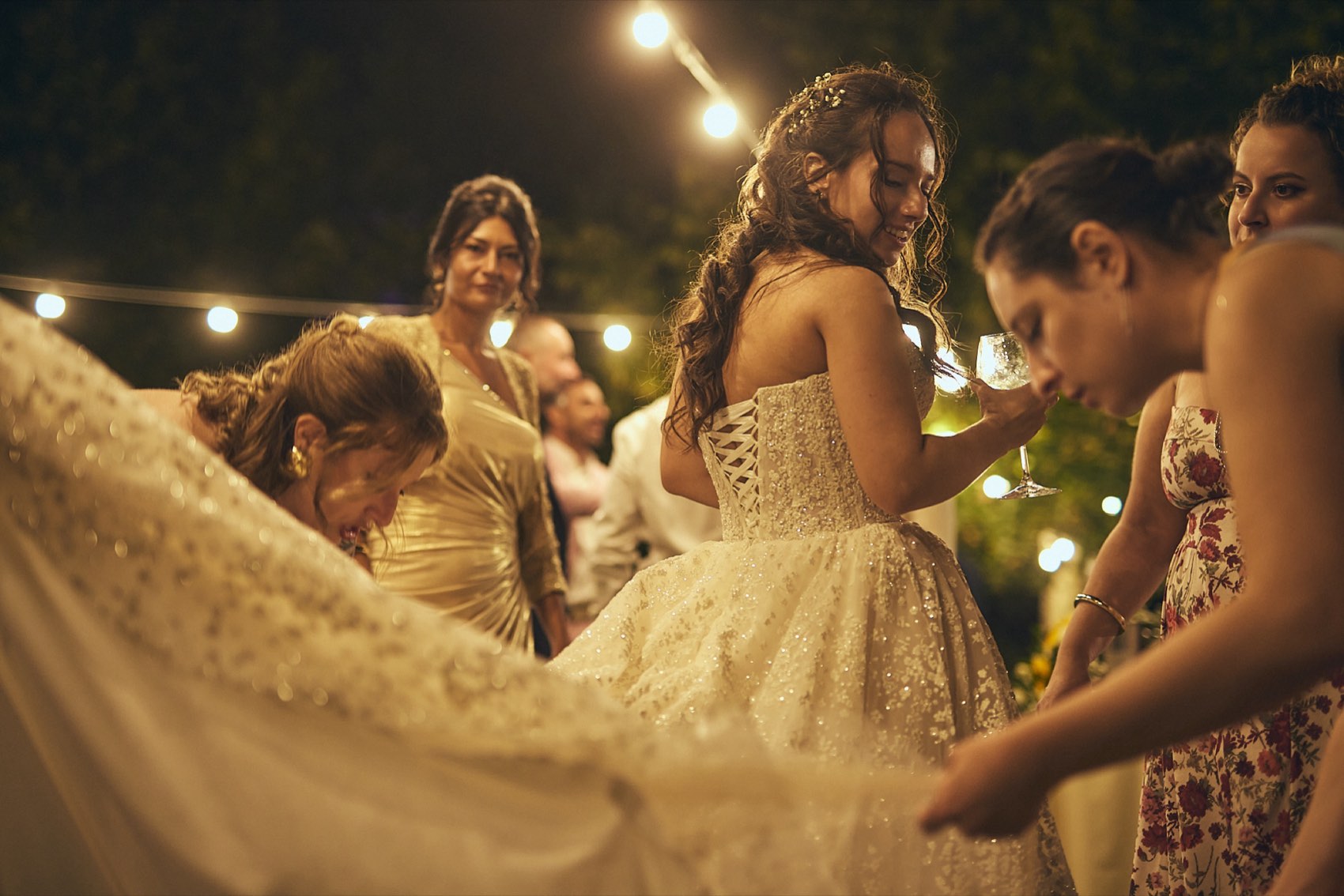 La sposa fra le amiche che le sistemano l'abito, durante la festa